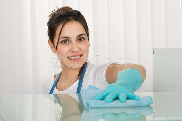 Szczęśliwy kobiet woźny czyszczenia biurko szmata Zdjęcia stock © AndreyPopov