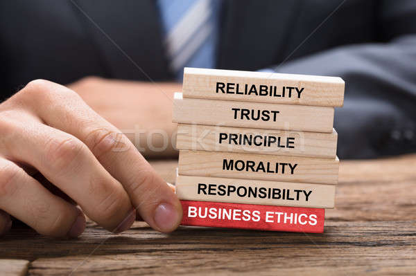 Stock photo: Businessman Holding Red Business Ethics Block Under Wooden Tower