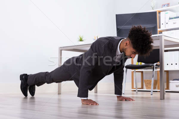 Businessman Doing Push Up In Office Stock photo © AndreyPopov