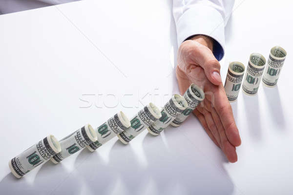 Person Stopping Falling Banknotes On Desk Stock photo © AndreyPopov