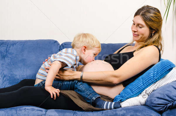 Little boy kissing belly of pregnant mother on sofa Stock photo © anmalkov
