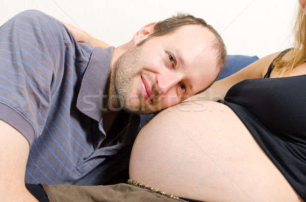 Happy husband lying on tummy of his pregnant wife on couch Stock photo © anmalkov