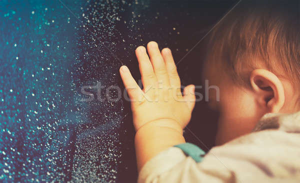 Stock photo: Baby looking through rainy window