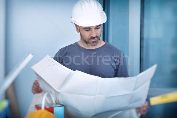 Stock photo: Architect builder studying layout plan of the rooms