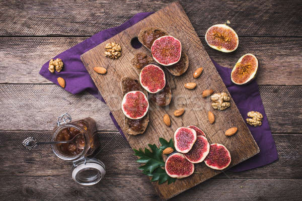 Stock photo: Sliced figs, nuts and bread with jam on choppingboard in rustic 