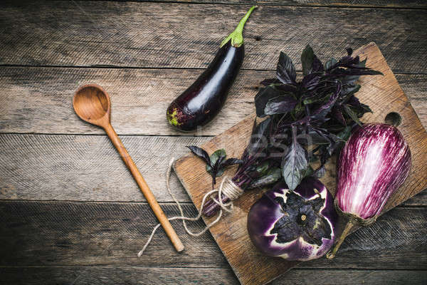 Aubergines and basil on chopping board in rustic style Stock photo © Arsgera