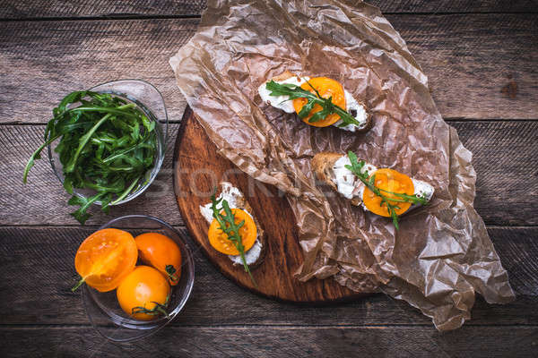 Bruschetta with tomatoes and salad rocket on board in rustic sty Stock photo © Arsgera