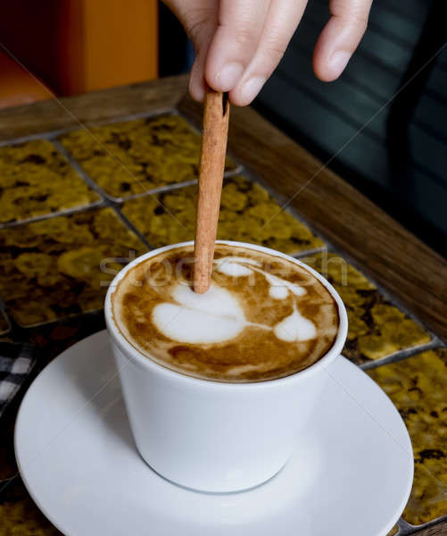 A coffee cup Latte being stirred by Cinnamon sticks. Stock photo © art9858