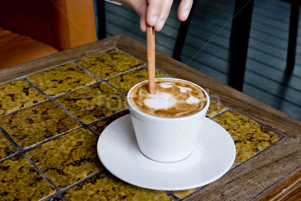 A coffee cup Latte being stirred by Cinnamon sticks. Stock photo © art9858