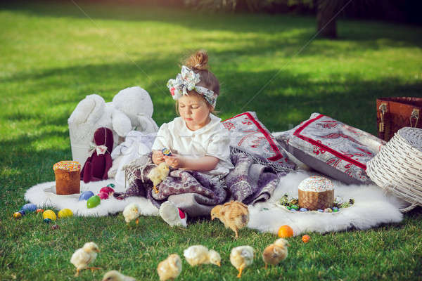 Stock photo: Child sits on a meadow around Easter decoration