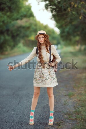 Stock photo: Girl with hat and backpack hitchhiking on the road