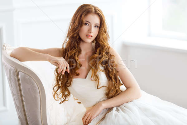 Bride in beautiful dress sitting resting on sofa indoors Stock photo © artfotodima