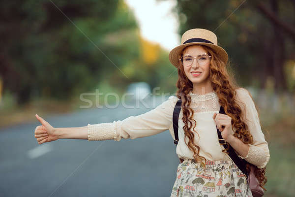 Girl with hat and backpack hitchhiking on the road Stock photo © artfotodima