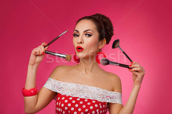 Surprised Woman with makeup brushes.   She is standing against a pink background. Stock photo © artfotodima