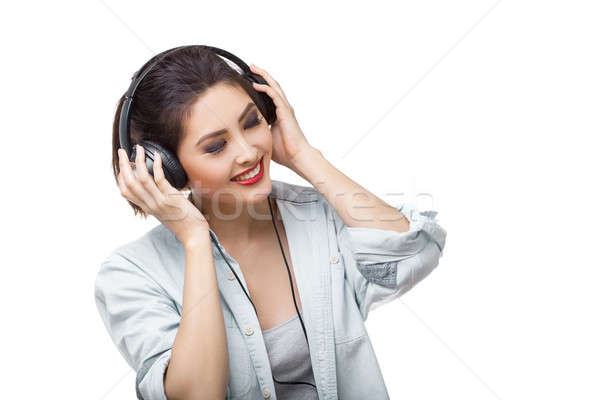 Young beautiful woman enjoy listening to music with big headphones isolated white background Stock photo © artfotodima