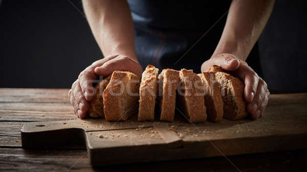 chef holding a bread in front of a wooden cutting board Stock photo © artjazz