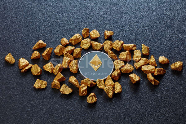 Gold nuggets and Etereum coin on a black concrete background. Business concept. Stock photo © artjazz