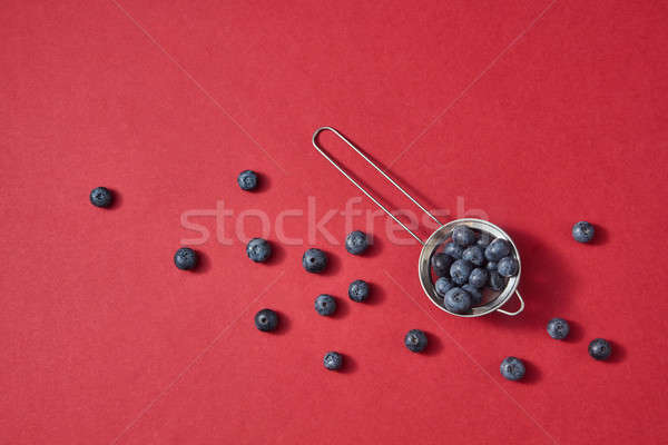 Ripe sweet blueberry in a colander a red paper background. Ntural beries pattern on a red. Stock photo © artjazz