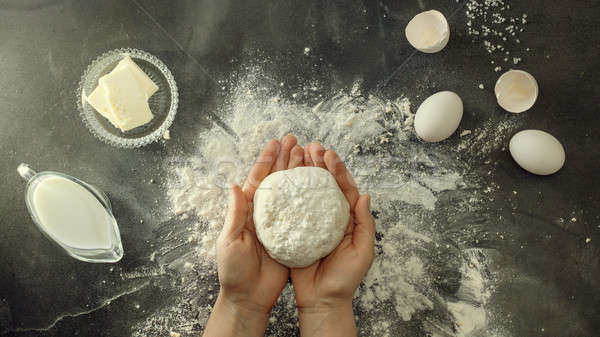 Woman's hands knead dough on table with flour Stock photo © artjazz