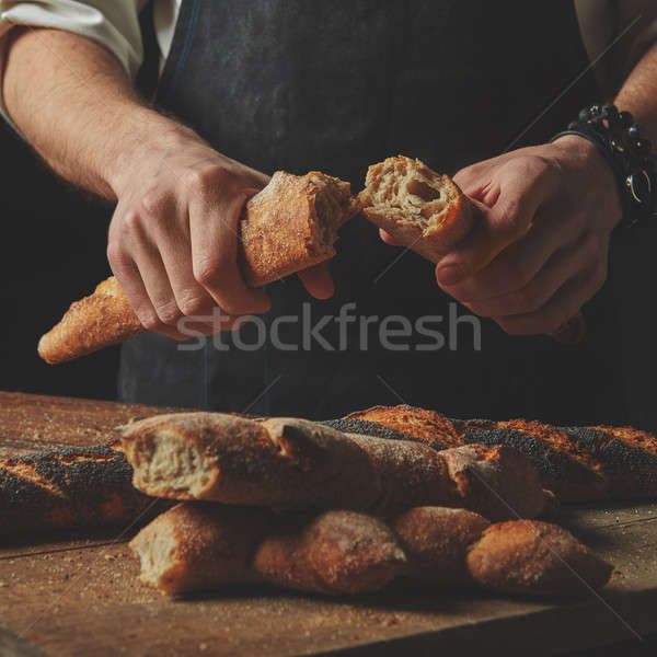 Male hands break the baguette Stock photo © artjazz