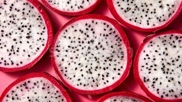 Flat lay view of background from round slices of Dragon fruit or Pitaya on a pink background. Stock photo © artjazz