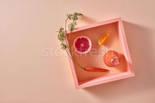 Orange smoothies from vegetables and fruits in a glass bottle and slices of citrus, carrot in square Stock photo © artjazz