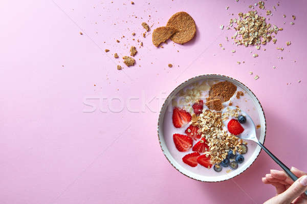 Woman's hands holding a spoon, bowl of organic yogurt smoothie with strawberries, banana, blueberry, Stock photo © artjazz
