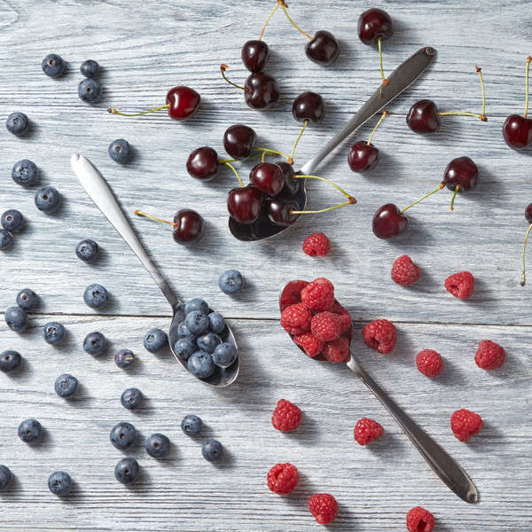 Mix of fresh organic berries pattern from blueberries, cherries, raspberries on a gray wooden backgr Stock photo © artjazz