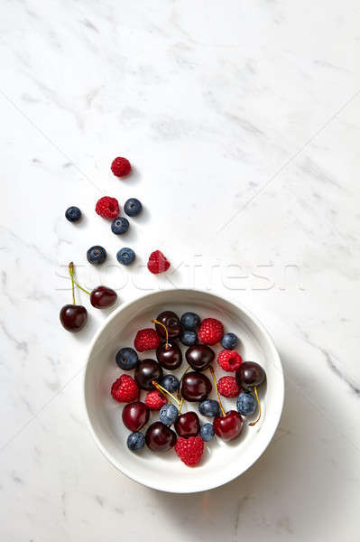 Sweet fresh blueberry, cherry, raspberry on a white plate on gray background with place for text. To Stock photo © artjazz