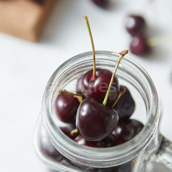 Close-up organic ripe red cherries in the glass jar on white background with soft focus. Stock photo © artjazz