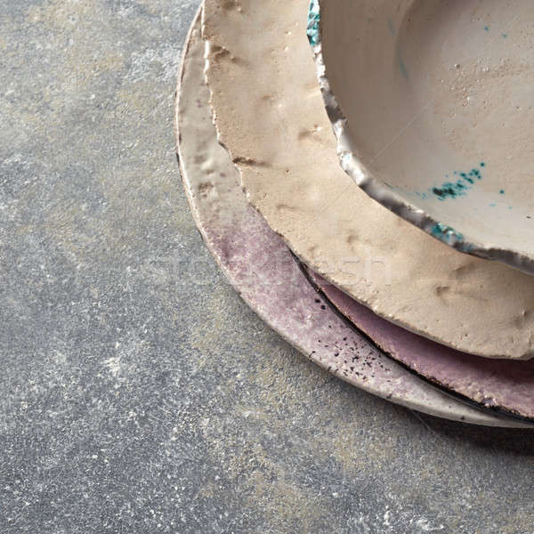 Handcrafted clay empty bowls and plates covered with glazed on a gray concrete background. Stock photo © artjazz