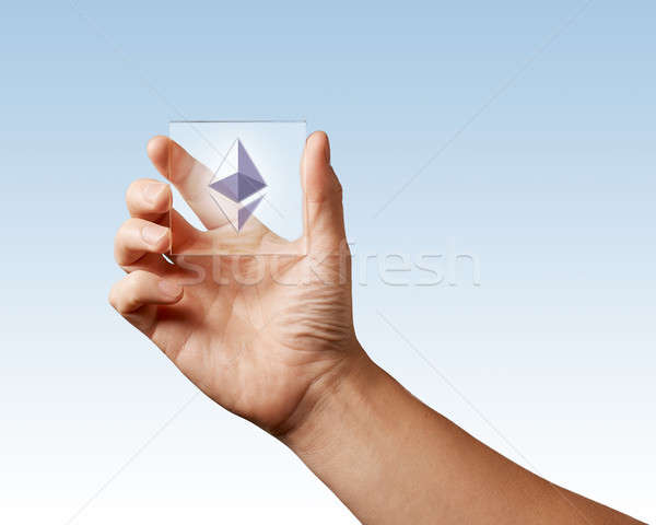 Icon of etereum on a digital screen man holds on a blue background Stock photo © artjazz
