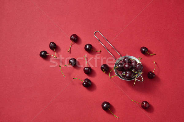 Colorfiul pattern with red juicy cherries on a red paper background. Top view Stock photo © artjazz