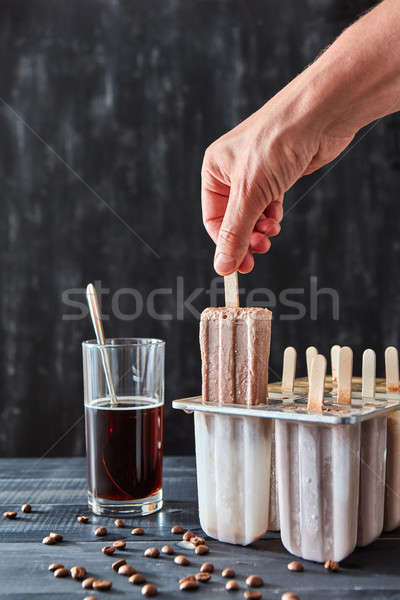 The girl's hand takes from the mold, homemade natural ice cream on a stick on a black wood table wit Stock photo © artjazz