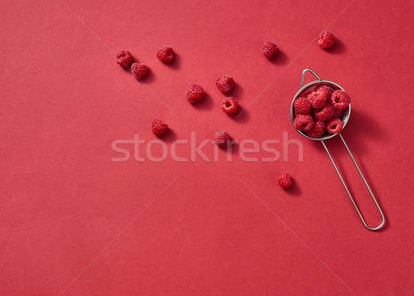 Fruits pattern of fresh summer raspberries on a red background. Top view. Stock photo © artjazz