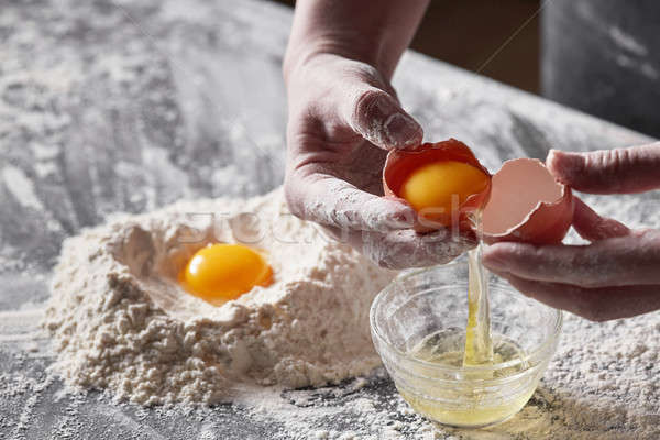 Female hands hold a broken egg in the hands of a kitchen table. Concept of baking Stock photo © artjazz