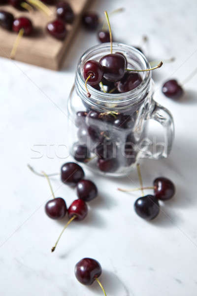 Close-up ripe sweet cherry in the glass cup, on a wooden board on white background with soft focus. Stock photo © artjazz