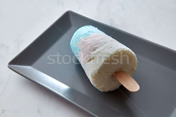 Close-up in a black plate a fruit colored ice cream on a stick on a gray marble table with space for Stock photo © artjazz