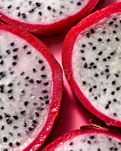 Close up view of background from round slices of Dragon fruit or Pitaya on a pink background. Stock photo © artjazz