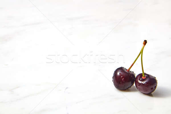 Two natural ripe sweet cherries in water droplets on a gray stone background. Place for text. Stock photo © artjazz
