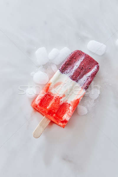 Vanilla berry sorbet on a stick with ice slices on a gray marble background with copy space. Top vie Stock photo © artjazz