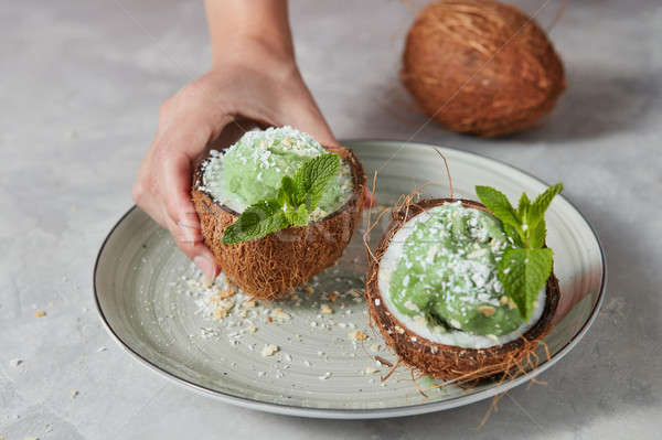 Womans hands take a half of coconut with homemade green ice crea Stock photo © artjazz