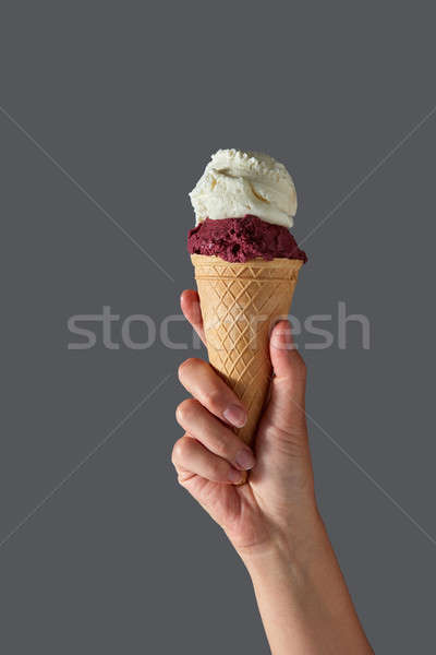 Red fruit sorbet and vanilla ice cream in the form of ball in waffle cone, which is held by a woman' Stock photo © artjazz