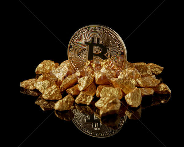 Studio shot of Bitcoin with gold nugget on a black reflective background .Digital virtual currency Stock photo © artjazz