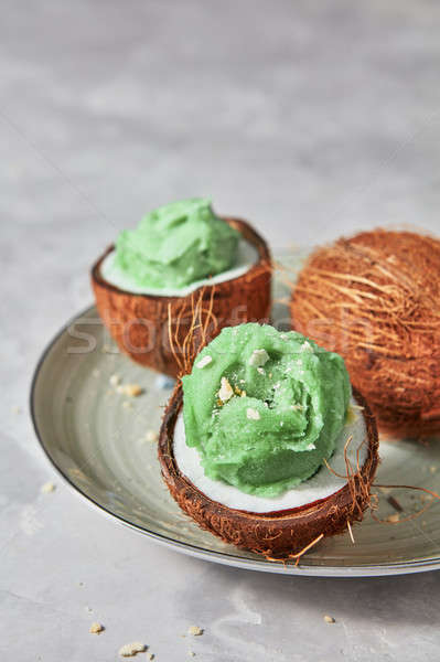 Delicious green ice cream in a coconut shell on a plate on a gra Stock photo © artjazz