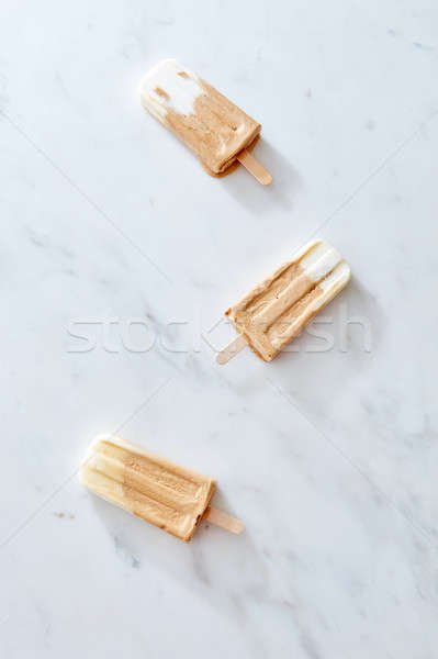 Three creme brulee coffee ice creams on a wooden stick over marble background, top view Stock photo © artjazz