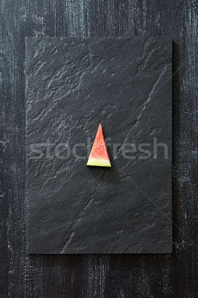 A piece of fresh watermelon on a black slate on a dark concrete background with copy space. Vitamin  Stock photo © artjazz