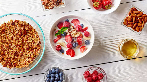 Cereal muesli and sliced bananas, strawberries, blueberries, raspberries, almonds and walnuts with m Stock photo © artjazz