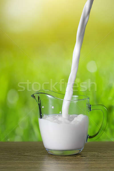Milk pouring into the glass on nature background Stock photo © artjazz