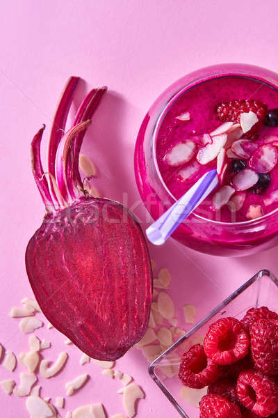 Homemade red smoothies with beet, raspberries and black currants, almond flakes on a pink paper back Stock photo © artjazz